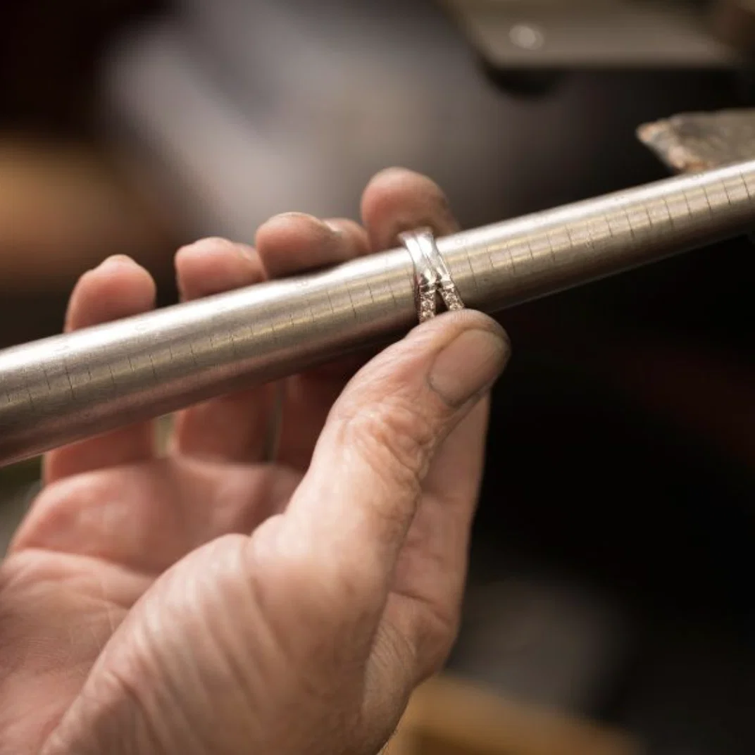 A jeweler carefully resizing a gold ring at the workbench